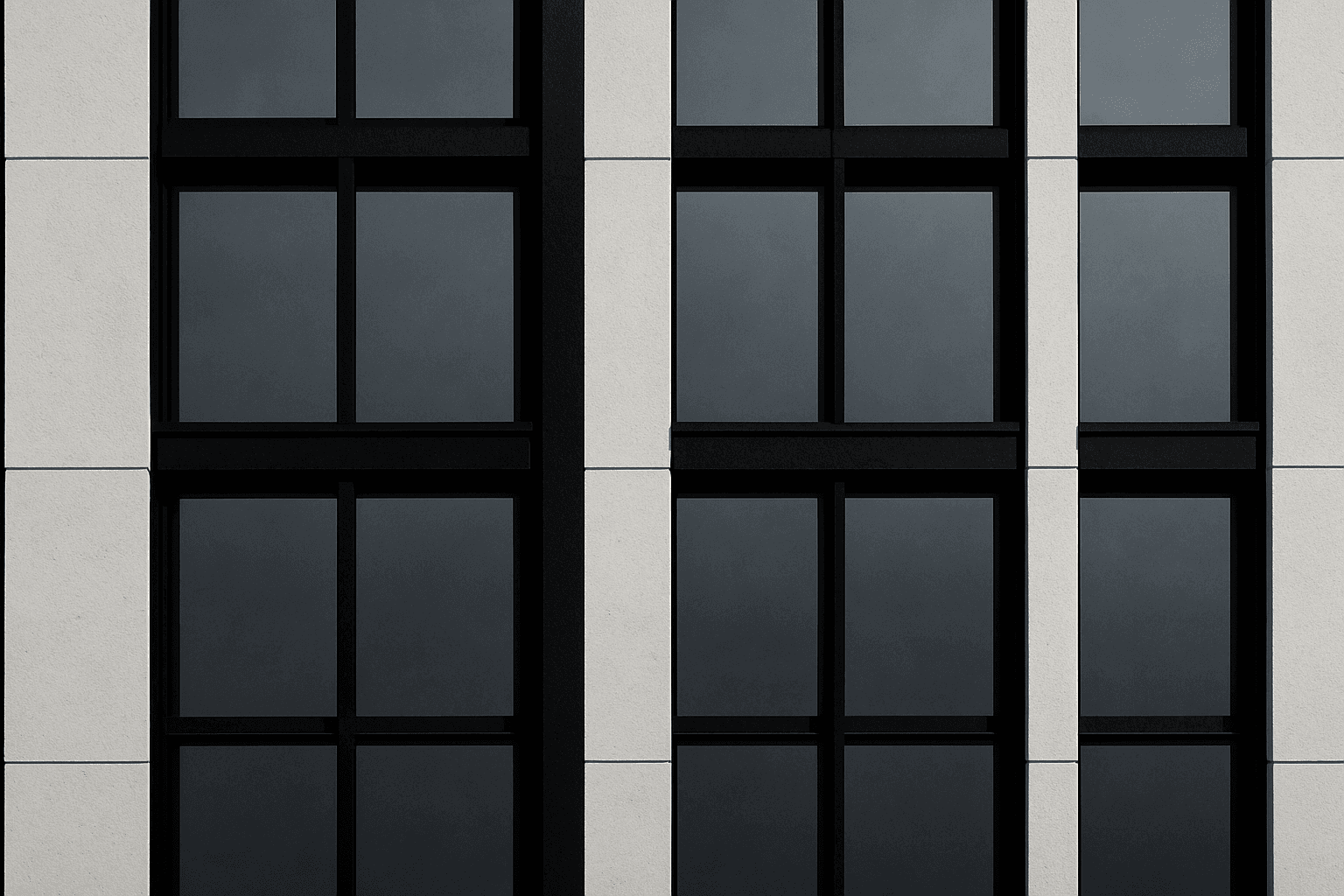 Close-up monochrome photograph of a curtain wall facade grid with steel-blue glass reflections